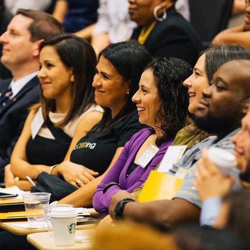 staff laugh in seats at symposium